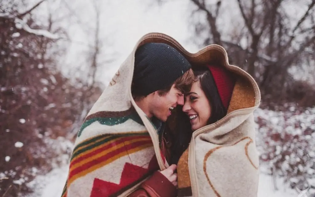 A guy with a girl under a blanket