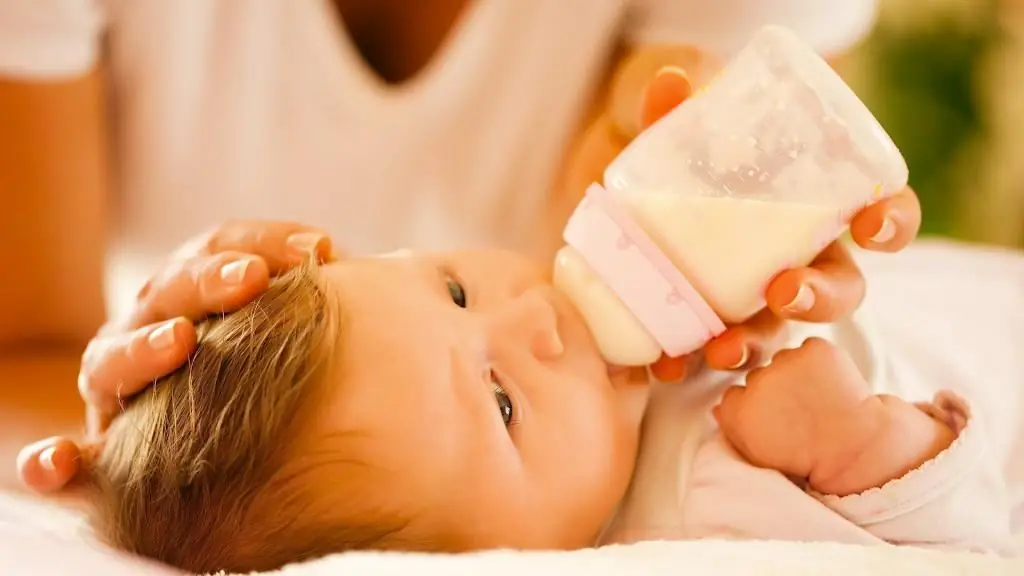 bambino che beve da una bottiglia sdraiato sulla schiena