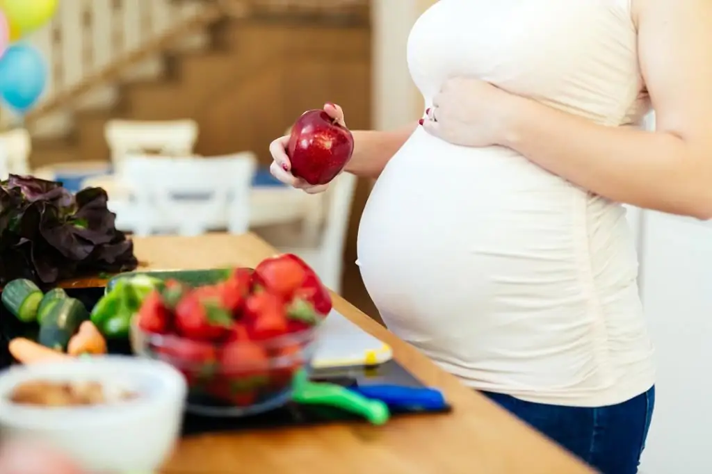 mujer embarazada comiendo una manzana