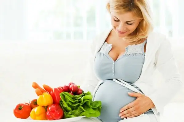 Chica embarazada cerca de verduras