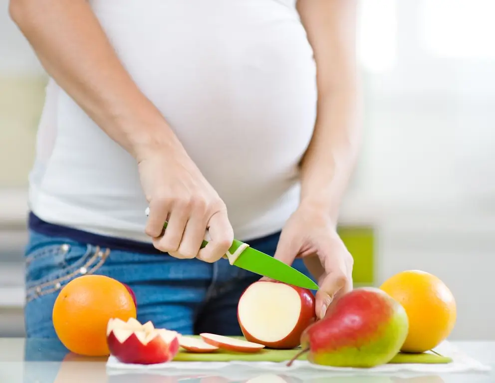 Chica embarazada corta una manzana